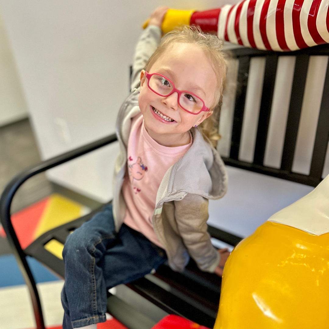 2019_tincher family Girl sitting on bench smiling.