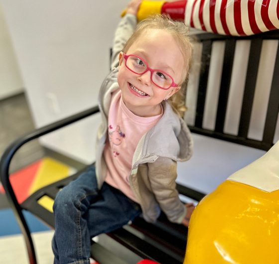 Girl sitting on bench smiling.
